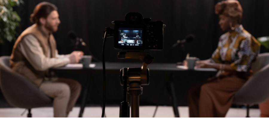 2 people sat at a table streaming a podcast.