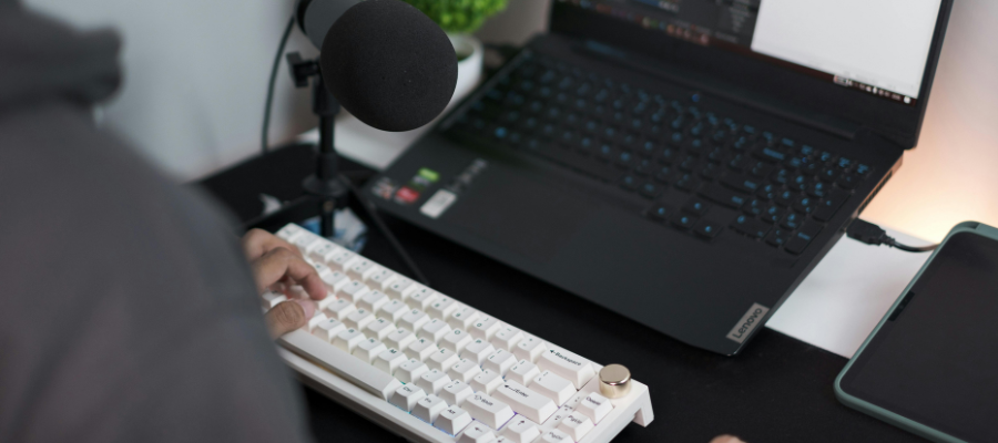 a white keyboard and a black laptop which someone is using.