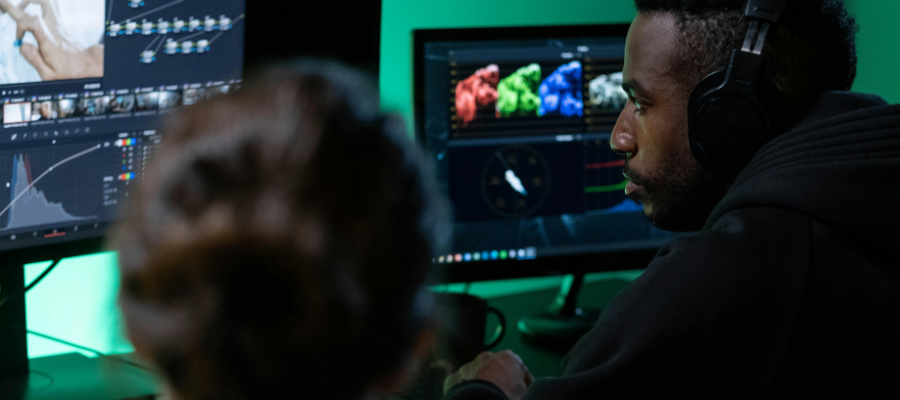 2 people editing a podcast with 2 monitors in front of them.